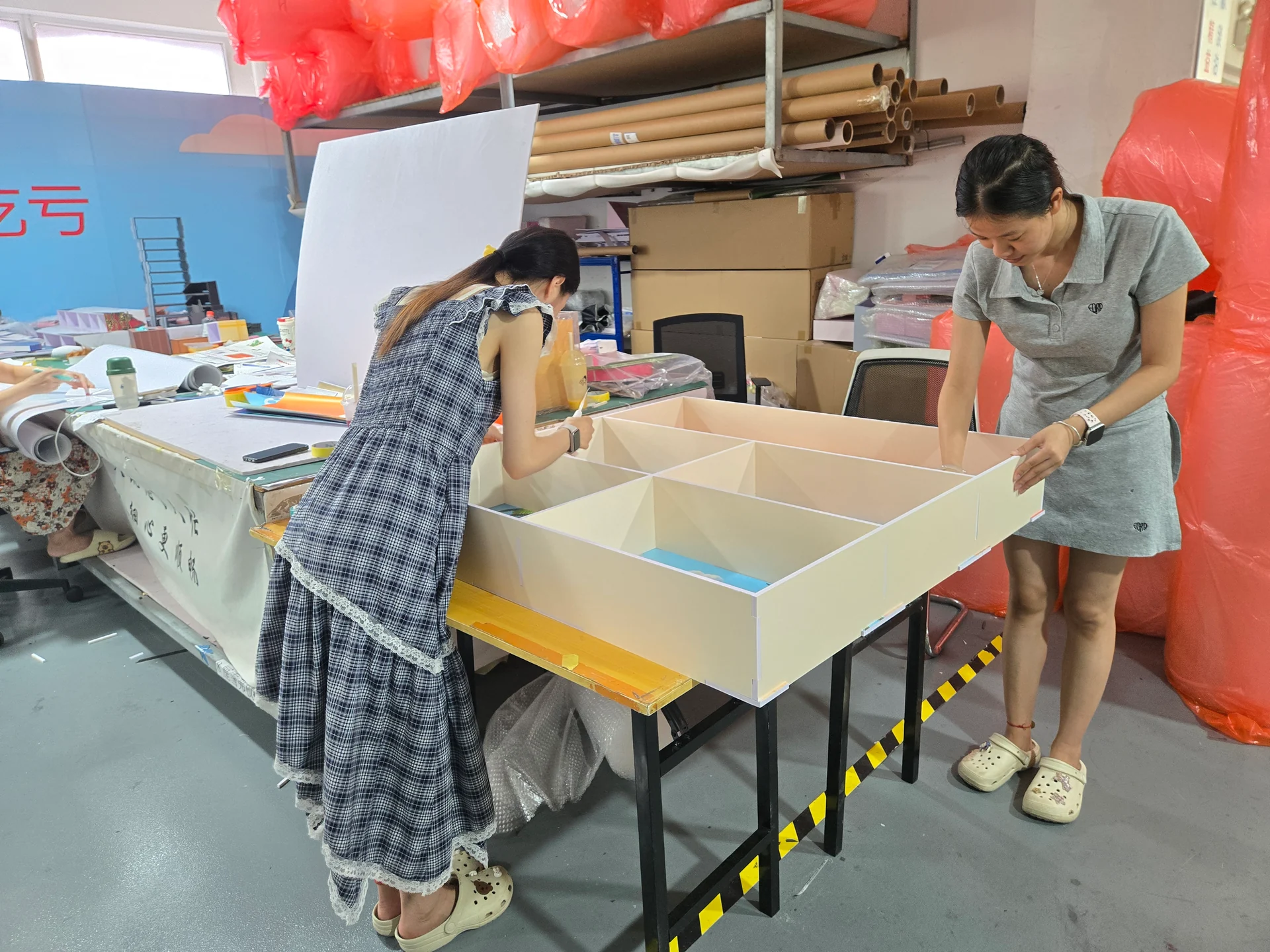 Two team members assembling a compartmented display structure